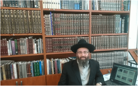 Reb Eliyahu Sitting by His Computer with His Torah Library in the Background